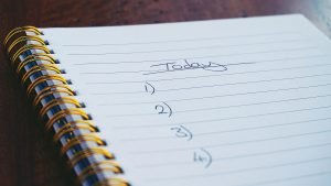 Stock photo of an open notebook with a checklist being written on it.